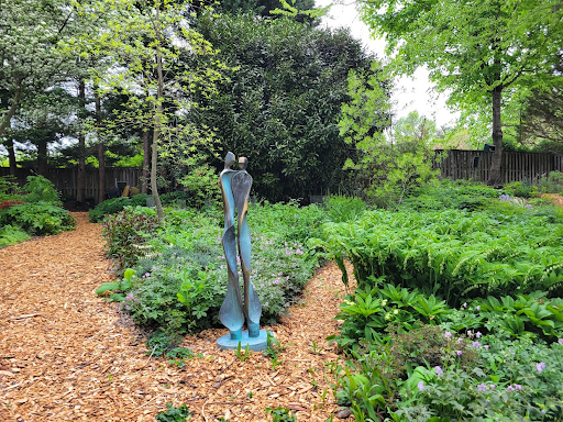 Modern statue of two figures in a lush garden